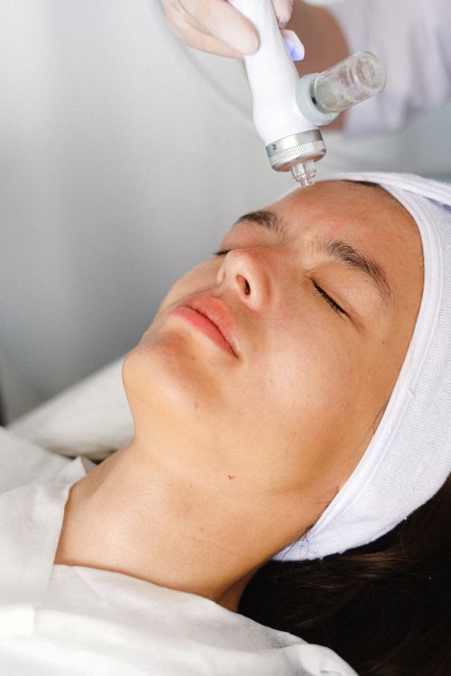 Especialista realizando procedimento facial com equipamento a laser em clínica de estética