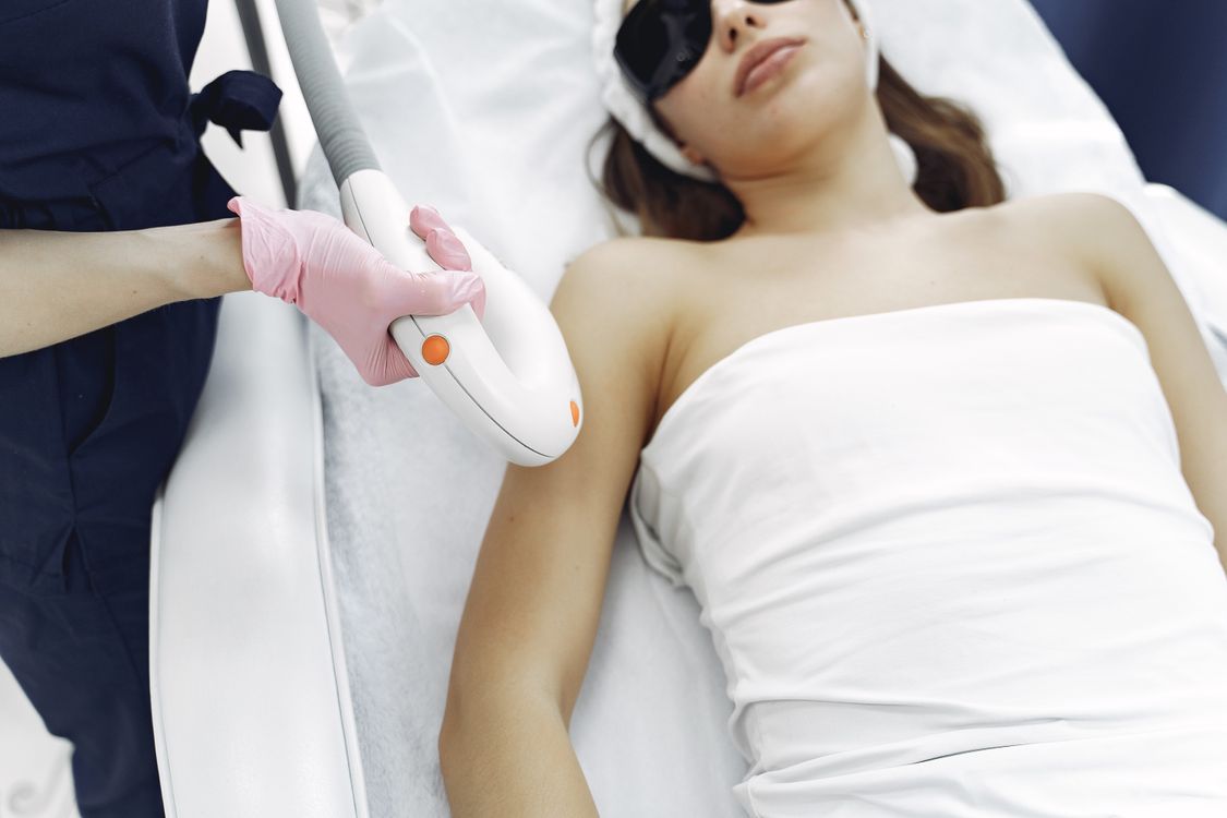 Esteticista aplicando depilação a laser em paciente usando óculos de proteção
