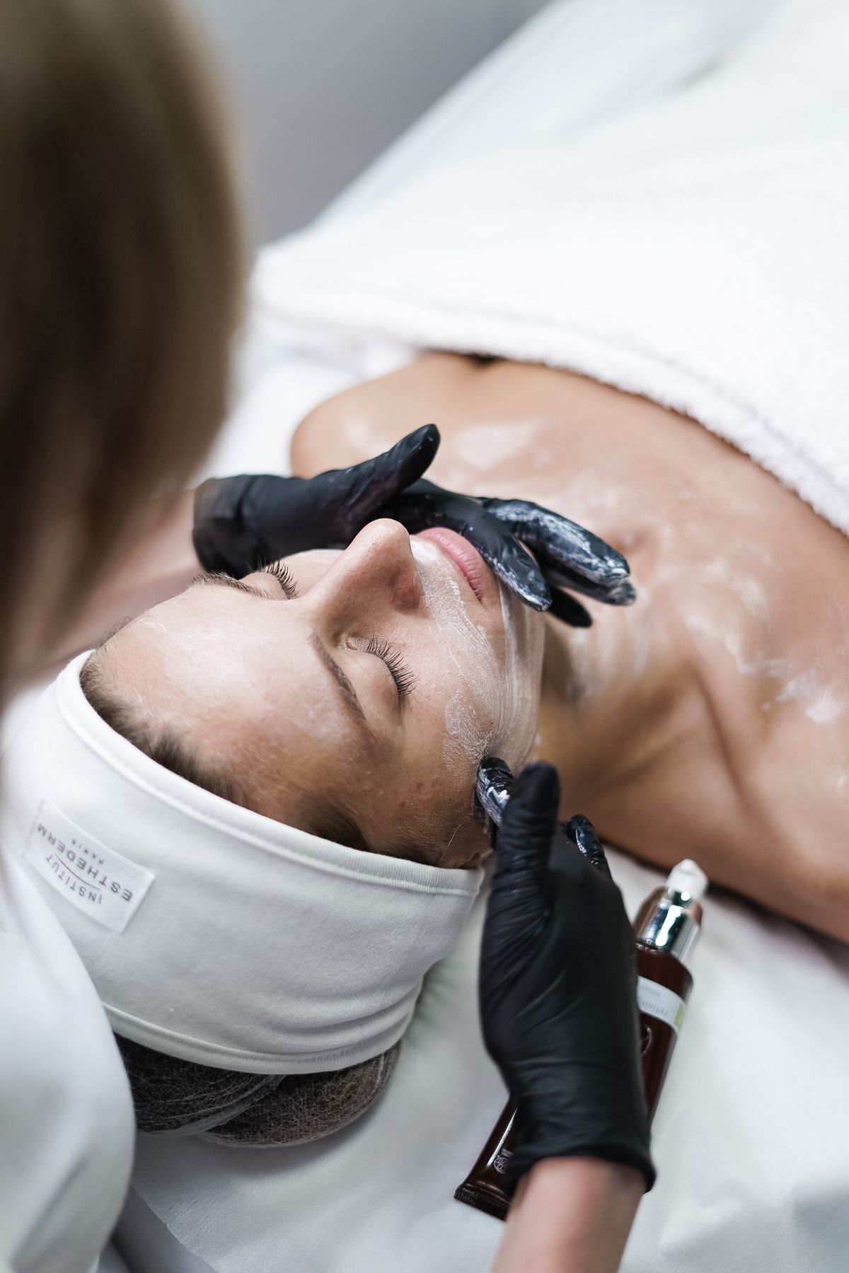 Profissional aplicando tratamento facial em paciente em ambiente de clínica